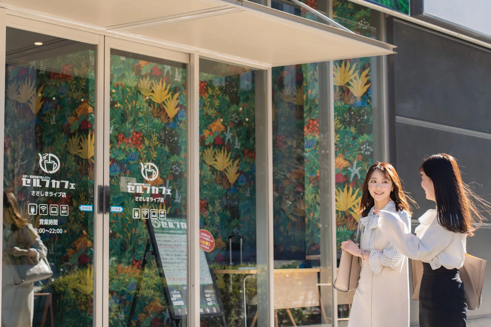 カフェの前で笑顔で会話する女性二人