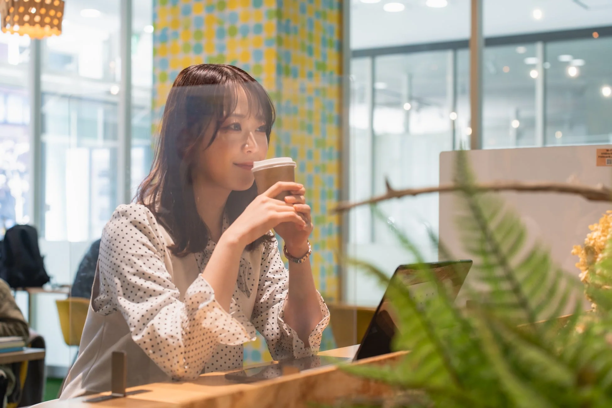 ノートパソコンとコーヒーでくつろぐ女性