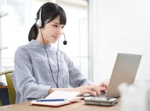 ヘッドセットを装着しノートパソコンを操作する女性