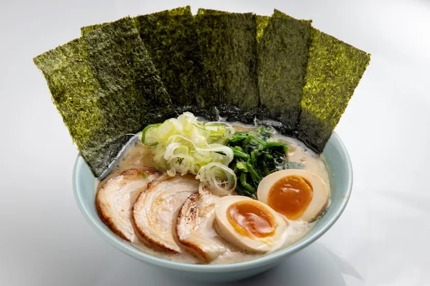 豚骨醤油ベースのスープに、チャーシュー、味玉、ほうれん草、ネギ、のりがたっぷり盛り付けられた家系ラーメンのクローズアップ画像。食欲をそそる温かい一杯です。