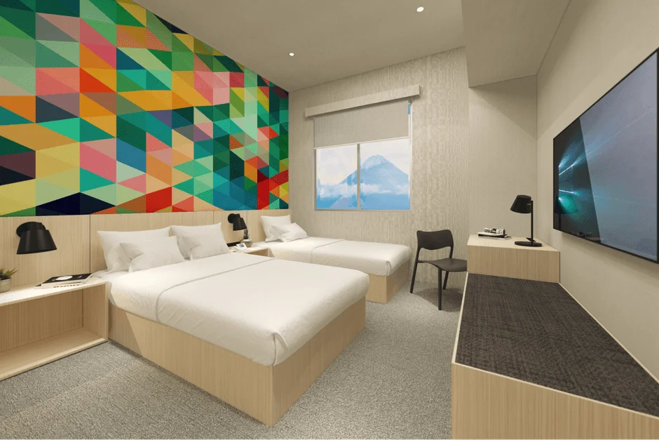カラフルな幾何学模様の壁が印象的なモダンなホテルのツインルーム