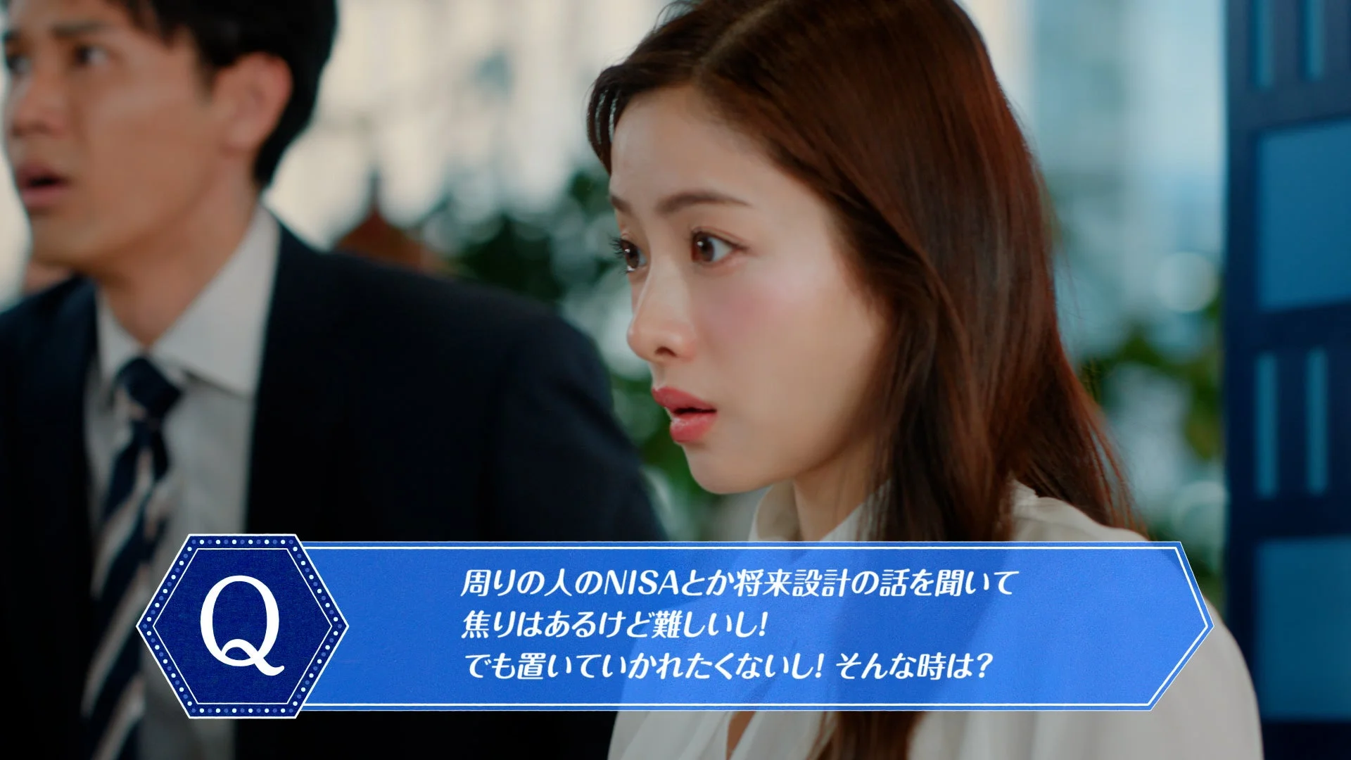 金融に関する質問が提示された場面で、一人の女性が真剣な表情で話を聞いています。NISAや将来設計について周囲の話を聞いて焦りを感じるが、難しさを感じ、置いていかれたくないという心情が表現されています。