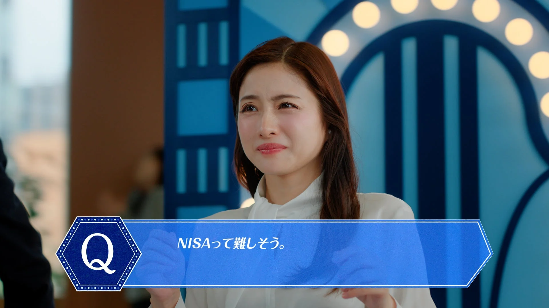 女性が少し困ったような表情でNISAについて「難しそう」と疑問を投げかけているシーン。青い背景と字幕が特徴的で、金融商品の広告や説明会の一場面のようです。
