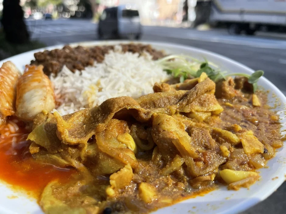 屋外で提供されたスパイスの効いたカレーとご飯のプレート料理