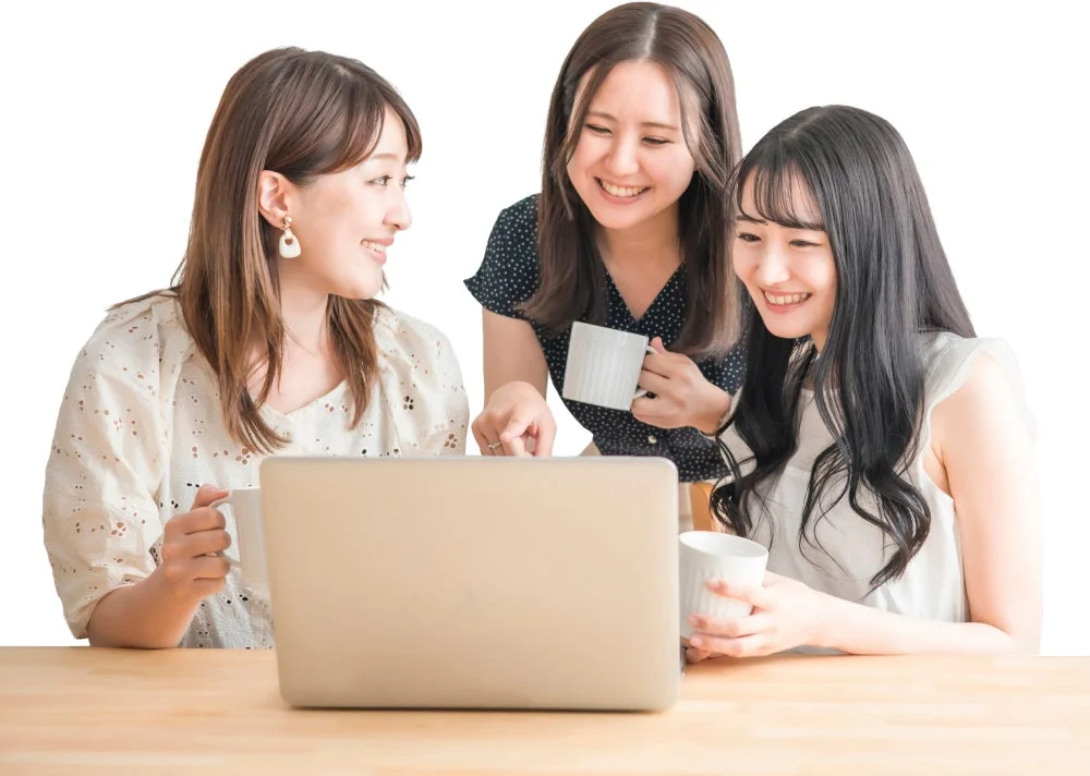 笑顔でラップトップの画面を見ながら会話する3人の女性