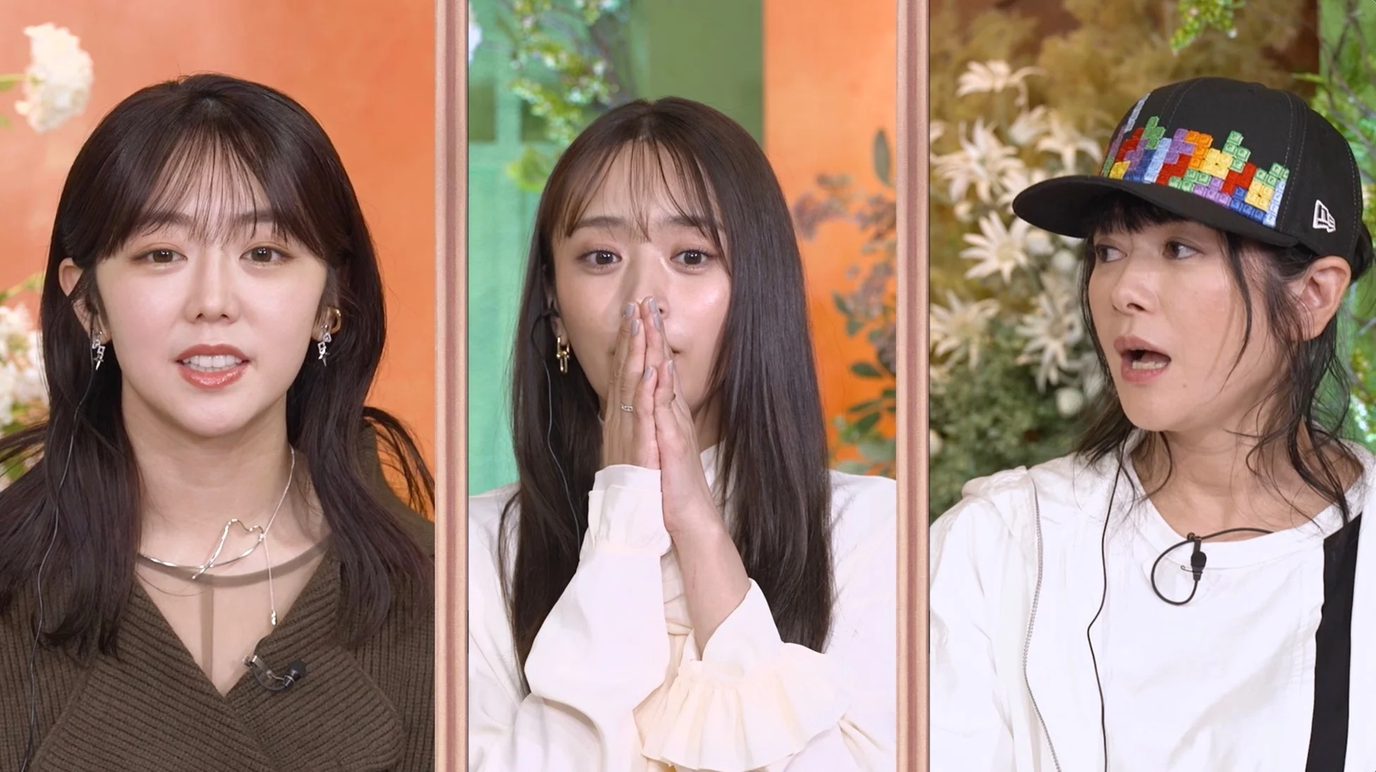 テレビ番組のスタジオで3人の女性がそれぞれ異なる表情を見せている様子