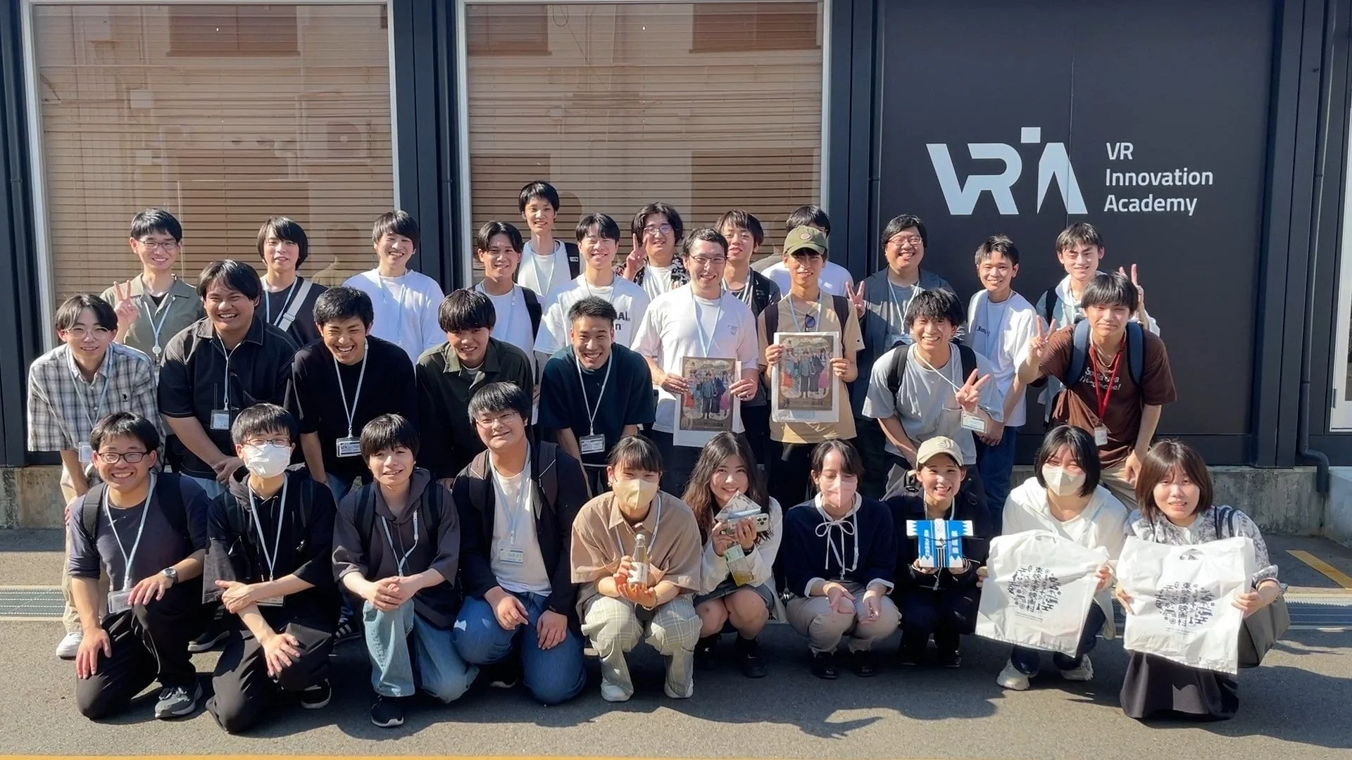 VR Innovation Academyの建物前で学生らしき若者たちが集合写真を撮っている様子