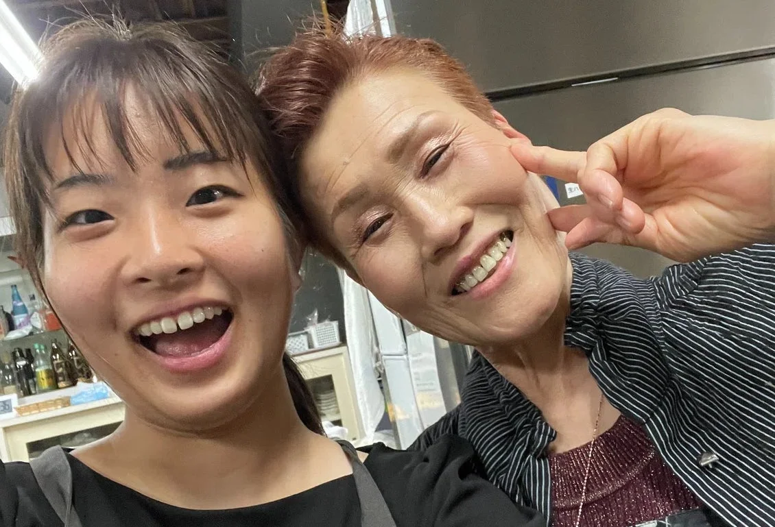 二人の女性が明るい笑顔でセルフィーを撮っています。