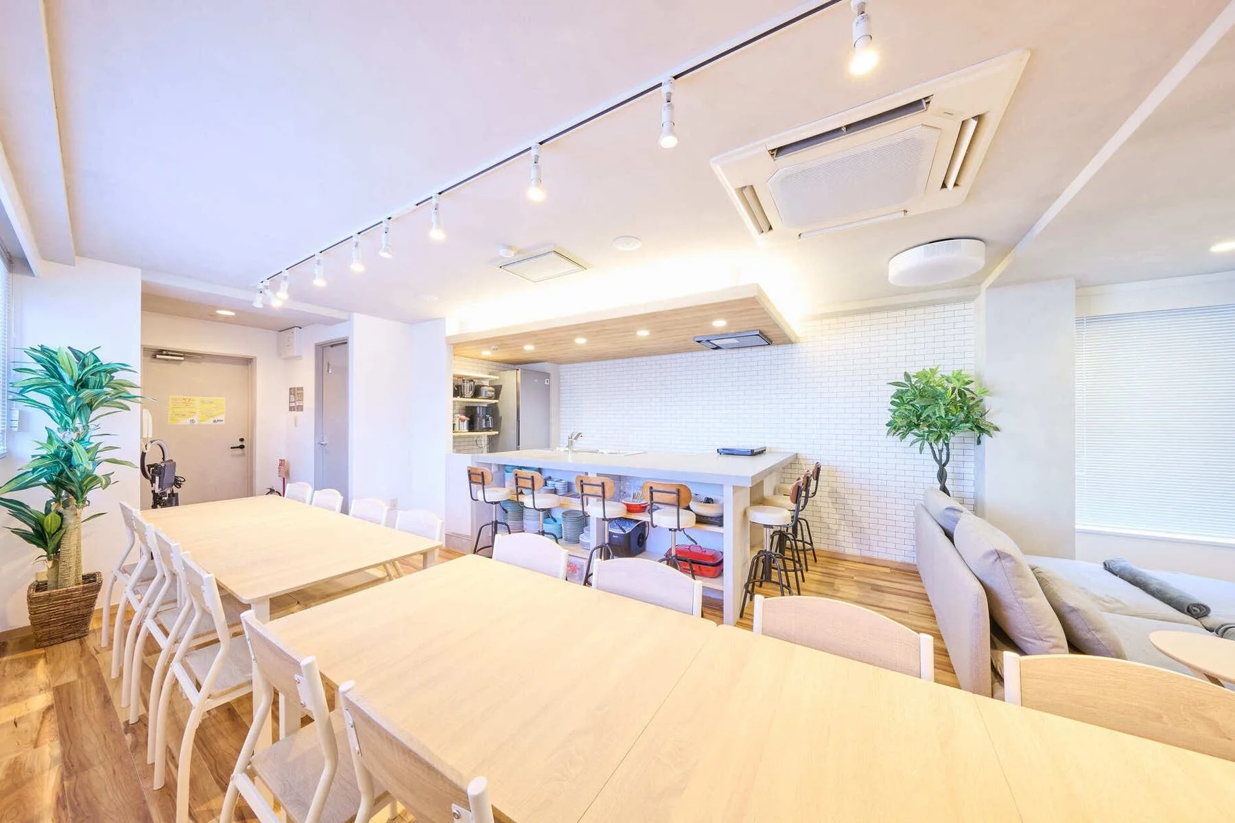 広々としたダイニングテーブルとキッチンカウンター、ソファエリアを備えた共用スペース