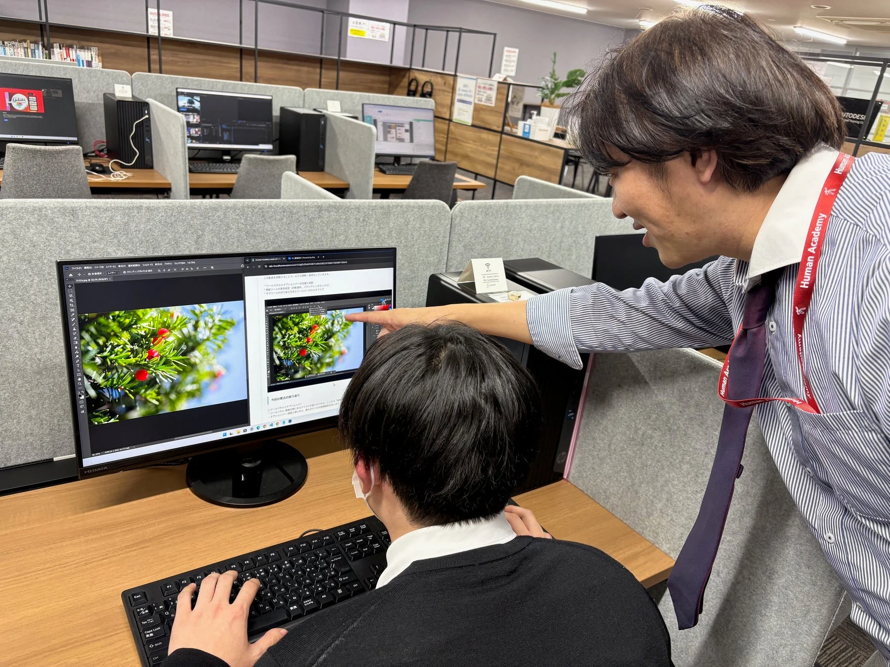 オフィスまたは教室でパソコンの画面を見ながら画像編集について学ぶ二人