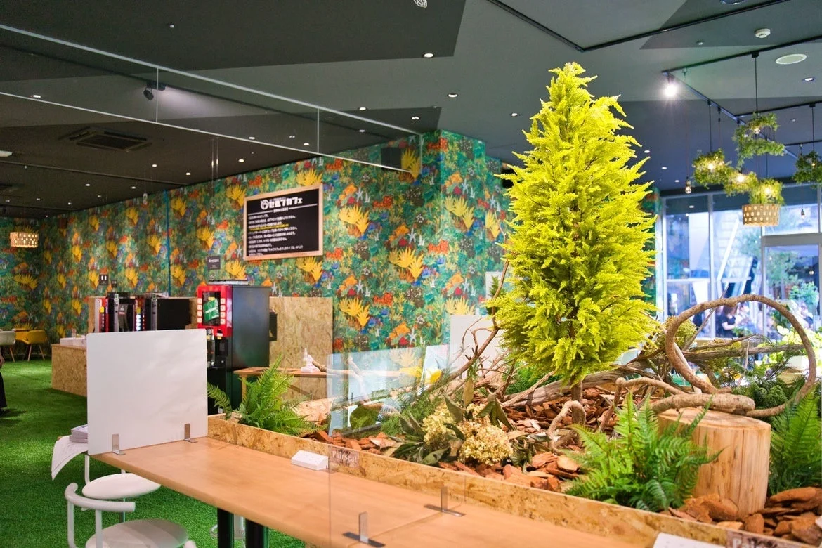 緑の人工芝と植物が特徴的なカフェのインテリア