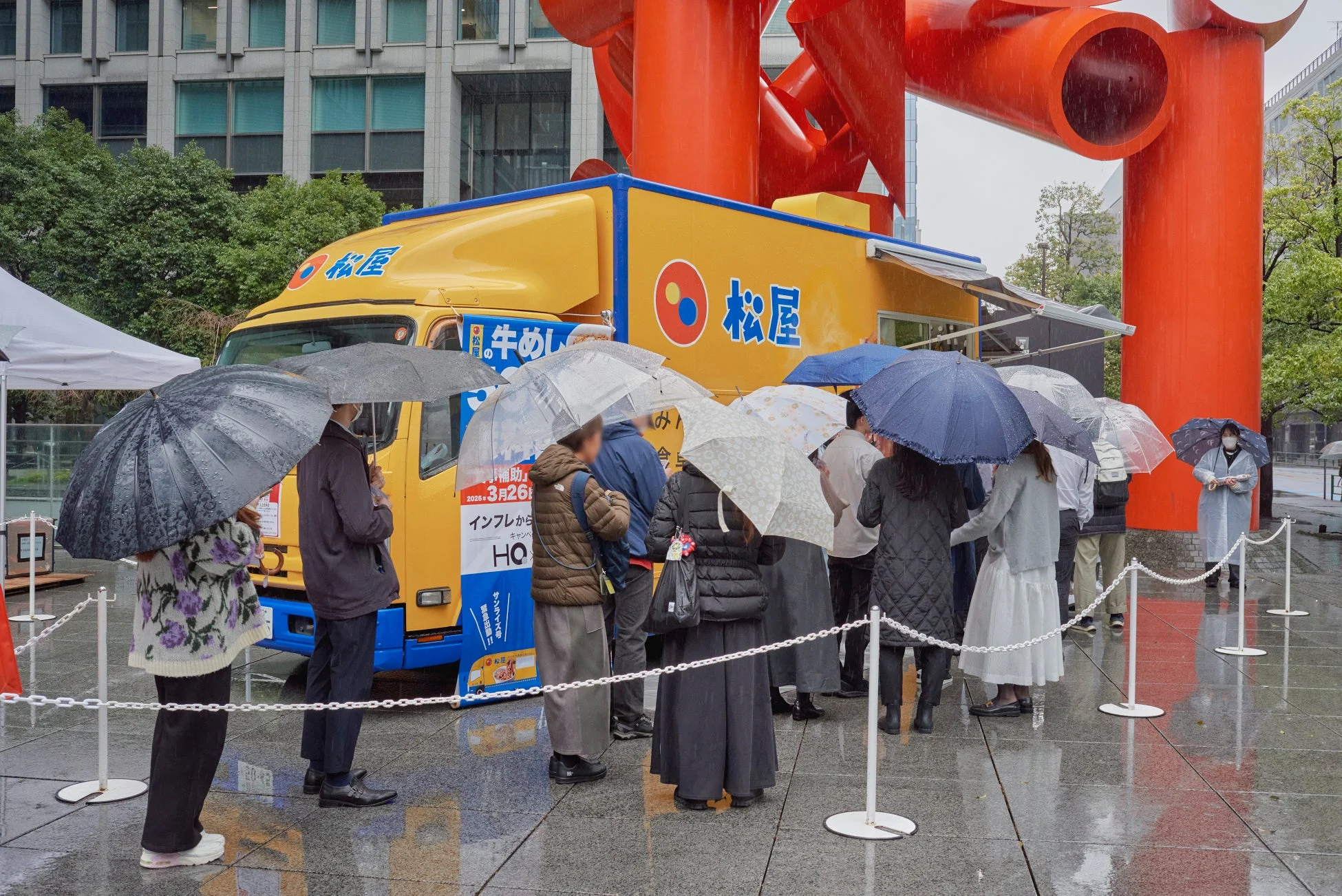 雨の中、フードトラックに並び、配布物を受け取る人々