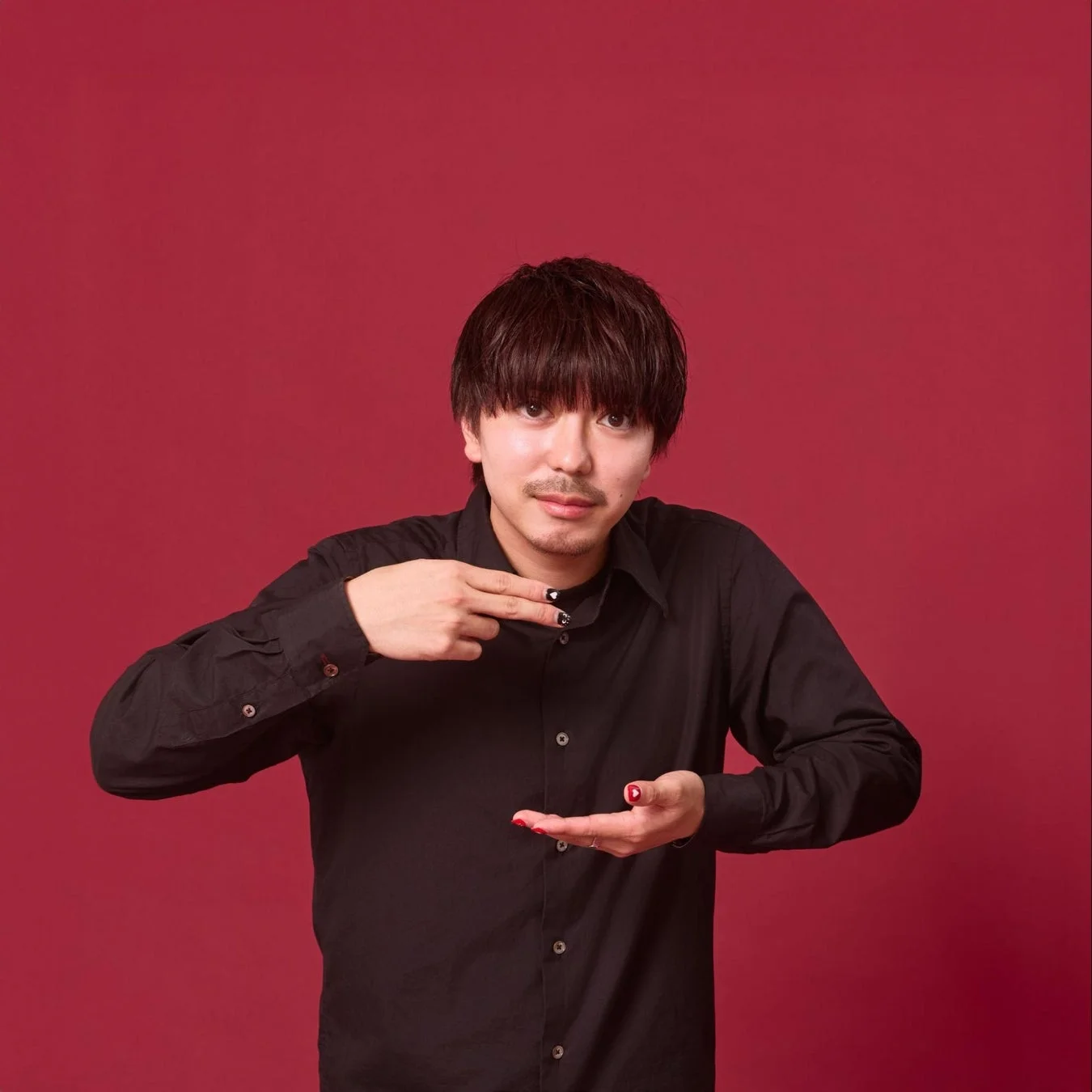 赤い背景の前で黒いシャツを着た男性のポートレート