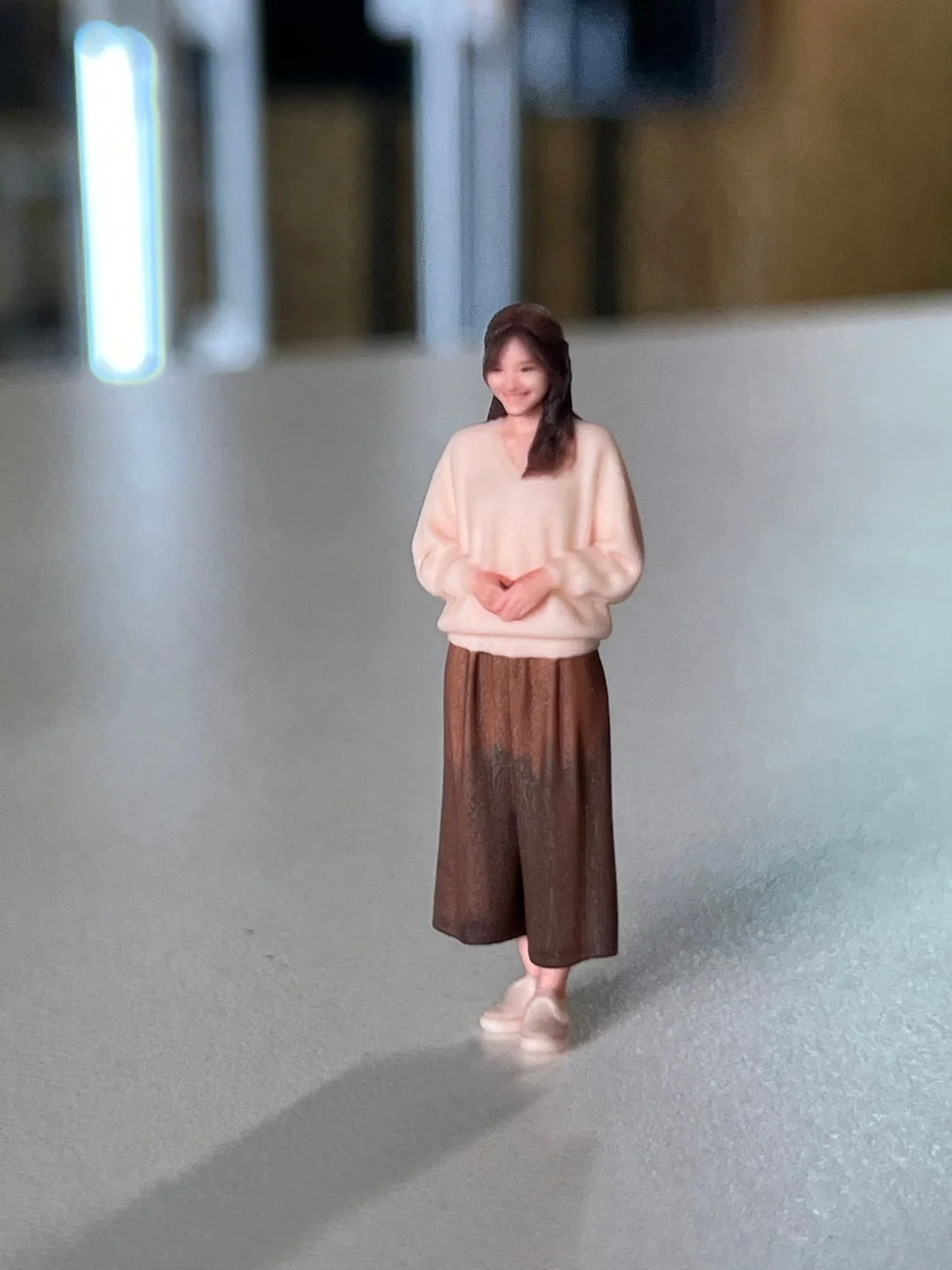 ピンクのセーターと茶色のガウチョパンツを着用した女性のミニチュアフィギュア