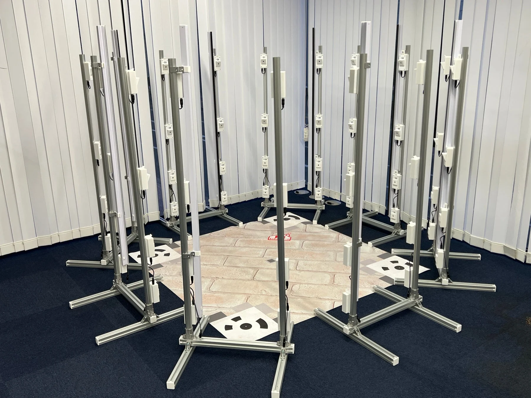 多数のセンサーやデバイスが取り付けられた垂直ポールが円形に配置された屋内スタジオ