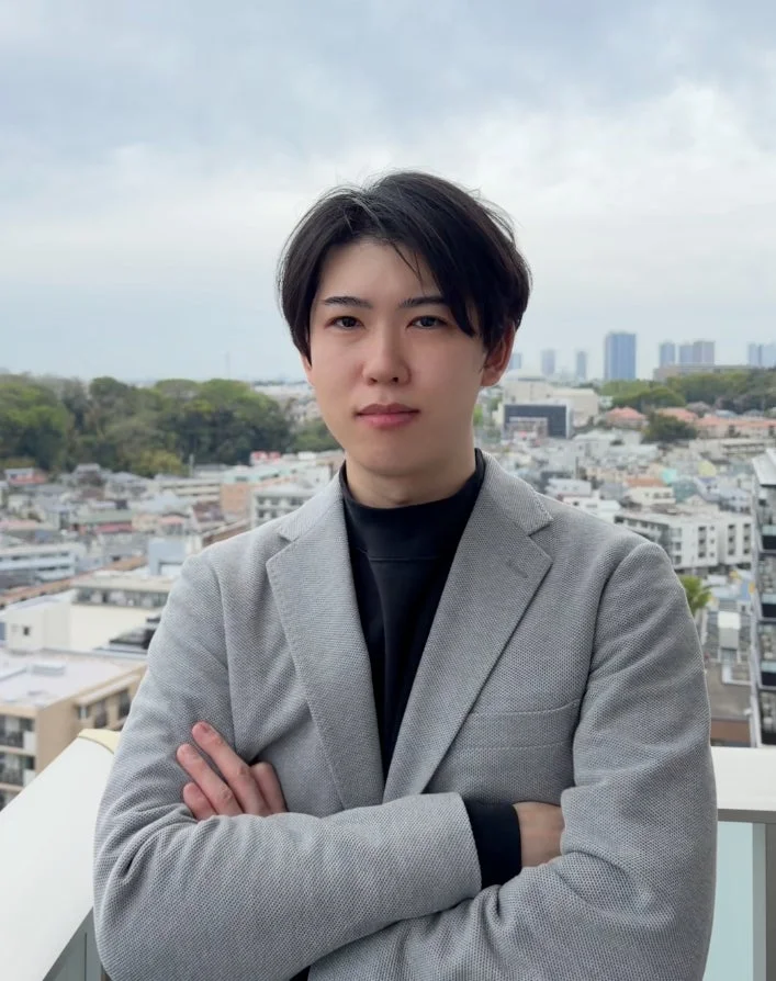 腕を組んで都市を背景に立つ男性