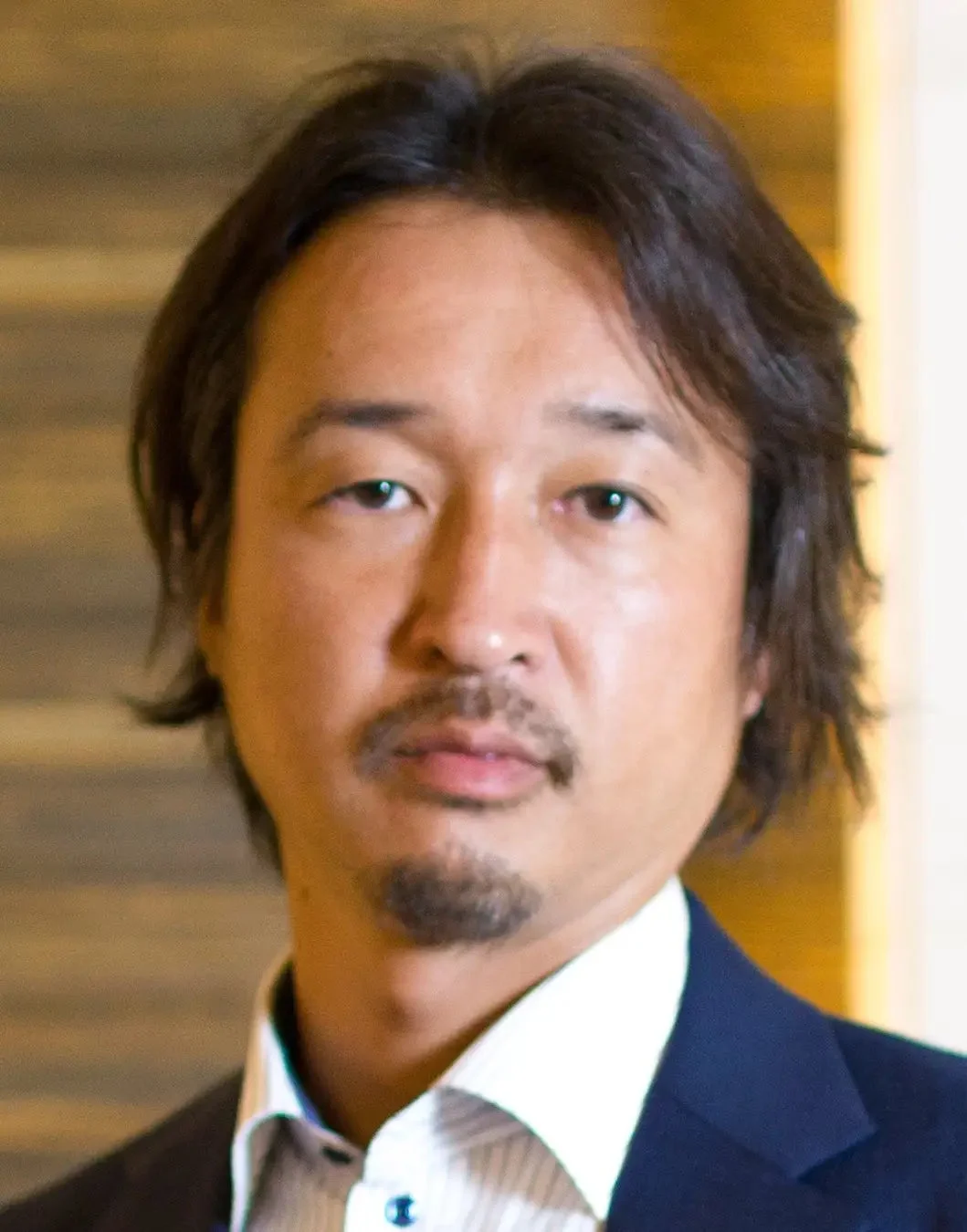 落ち着いた表情のアジア人男性の胸から上のポートレート