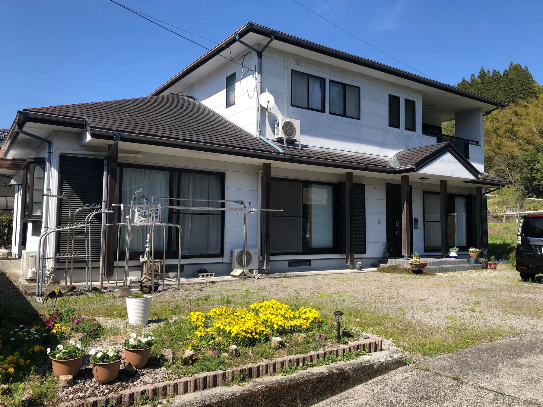 庭に黄色い花が咲く二階建ての一軒家