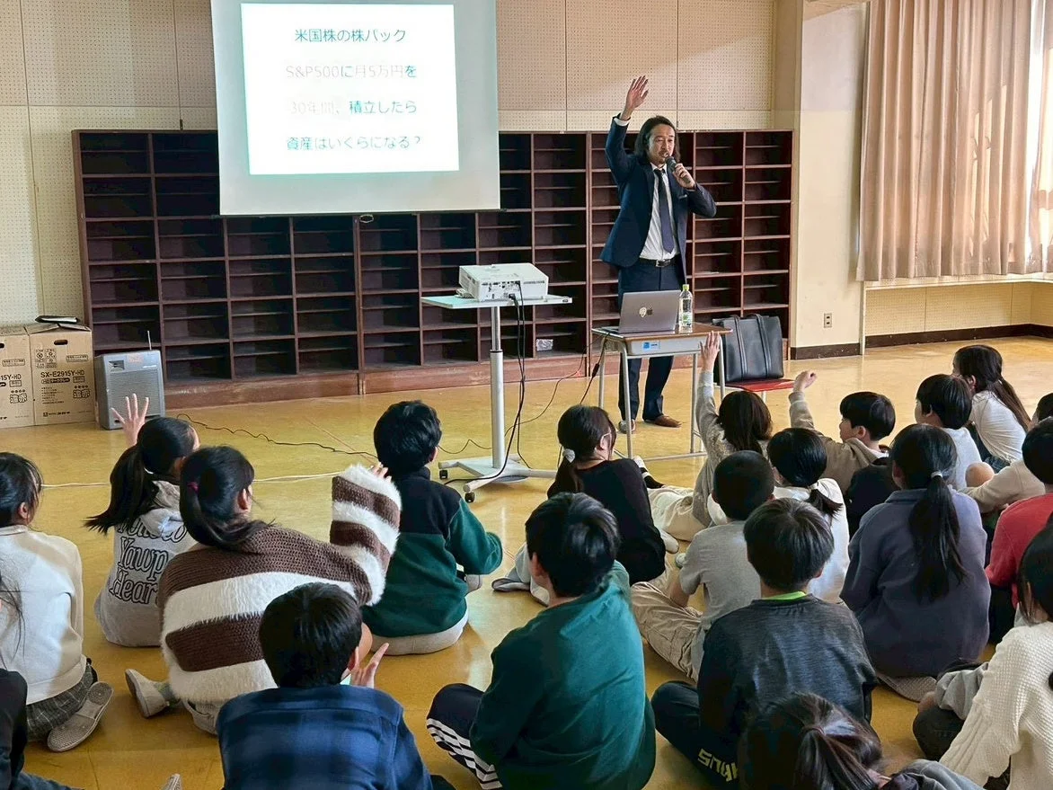 男性が子供たちに金融教育の講演を行っている様子