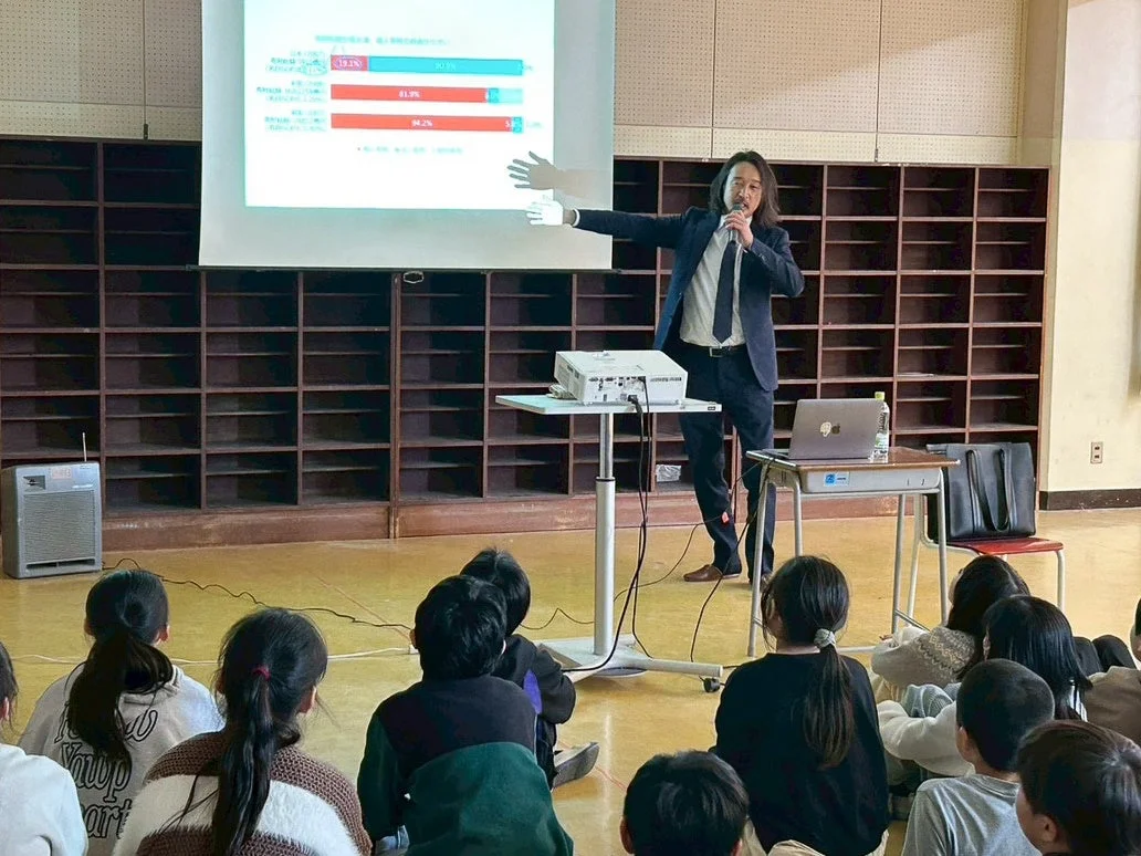 スーツ姿の男性が子供たちにプレゼンテーションを行っている様子