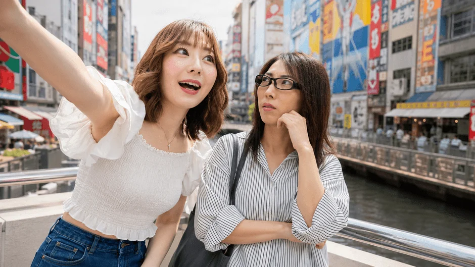 日本の賑やかな街を訪れた二人の女性が、橋の上で観光を楽しんでいる画像