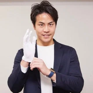 スーツジャケットと白Tシャツを着た男性が白い手袋を着用している様子