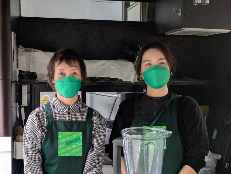 厨房でブレンダーを前に立つスタッフ