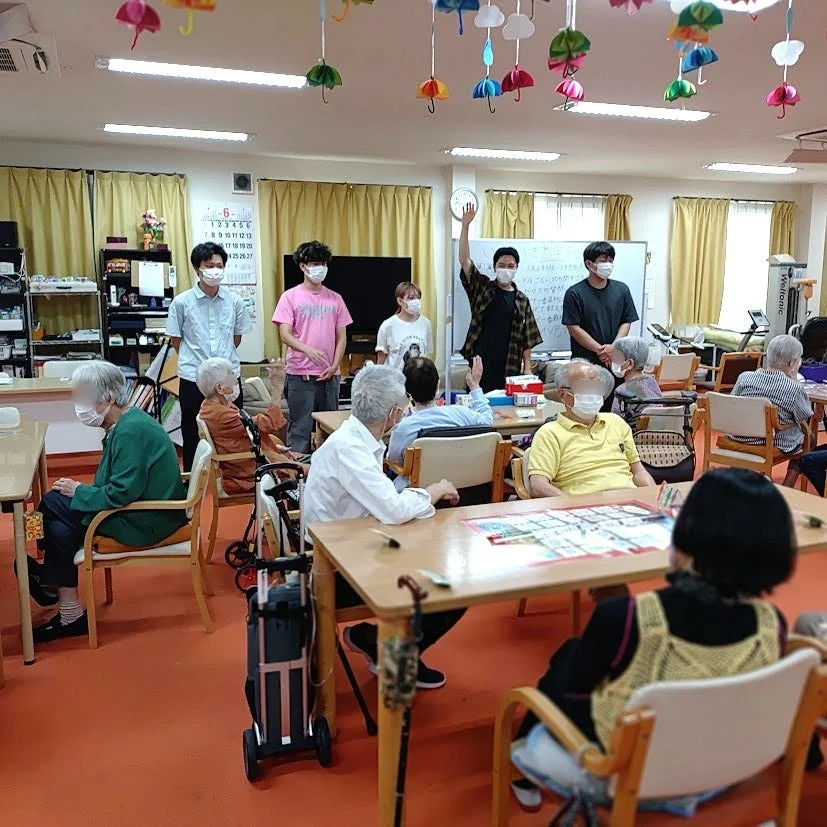 高齢者と若者がカラフルな傘の下で交流する様子