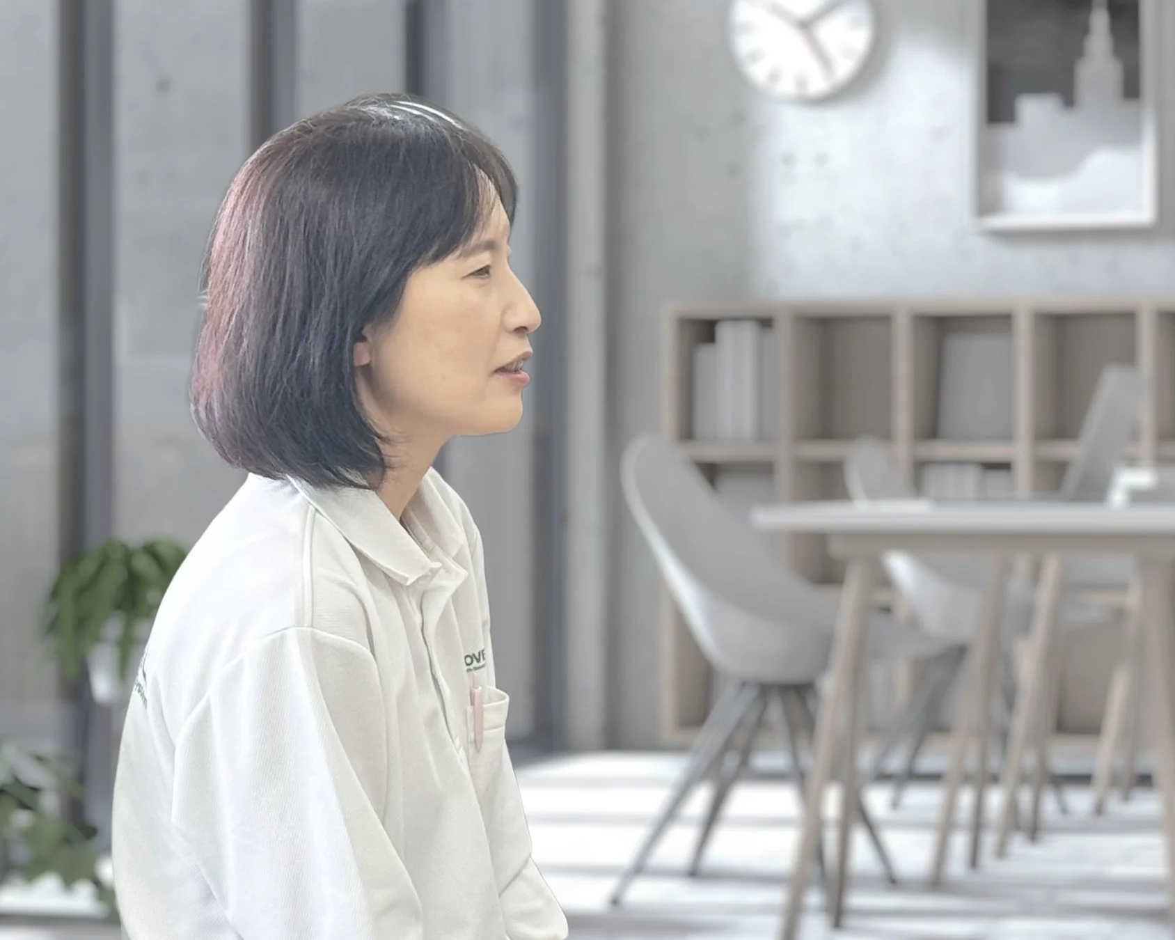 白いポロシャツを着たショートヘアの女性が話している様子